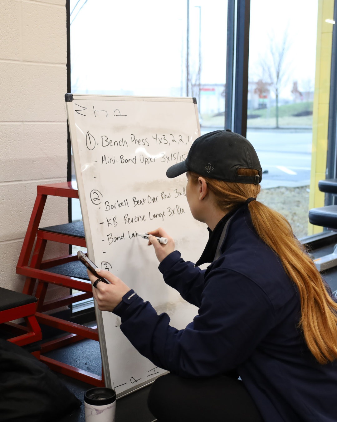 Instructor writing down the day's workout plan on a white board.