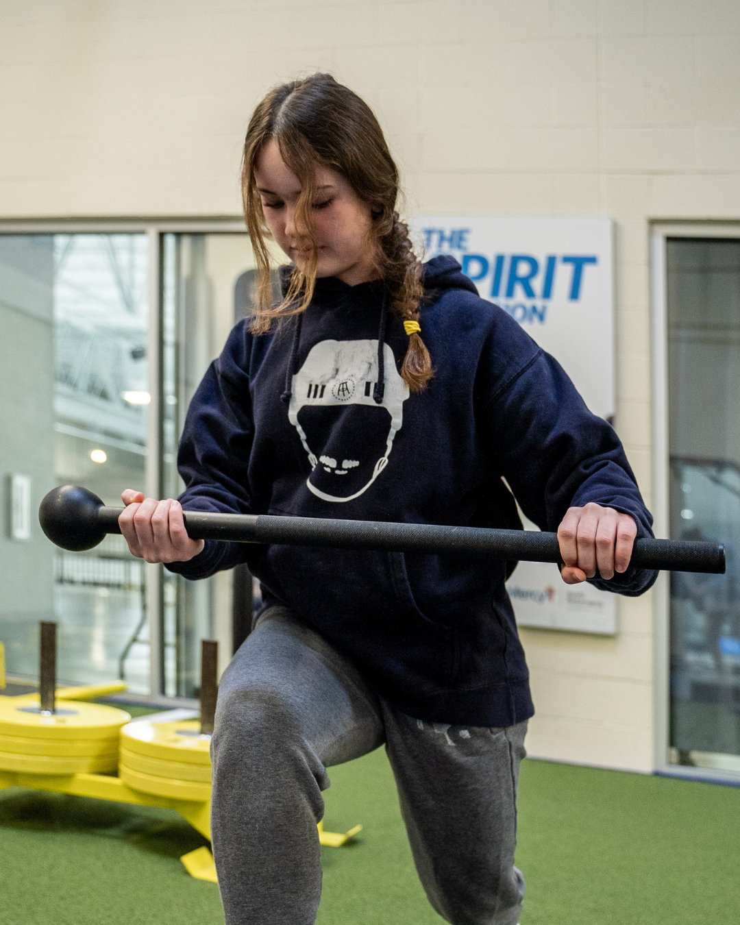 Female student-athlete in a lunge position while working through an exercise in the weight room.