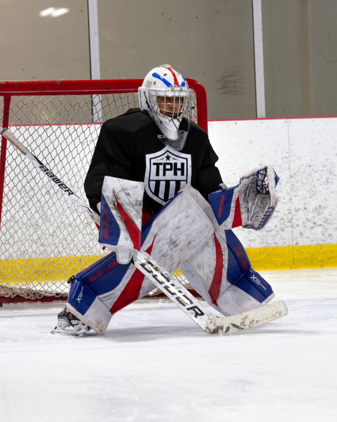 Hockey goalie standing ready in net for an oncoming shot.