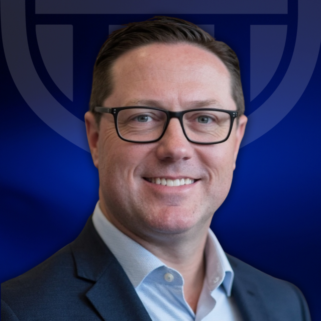 A smiling man with short brown hair and glasses, wearing a dark suit jacket and light blue shirt, poses in front of a dark blue background featuring the TPH Academy logo design.